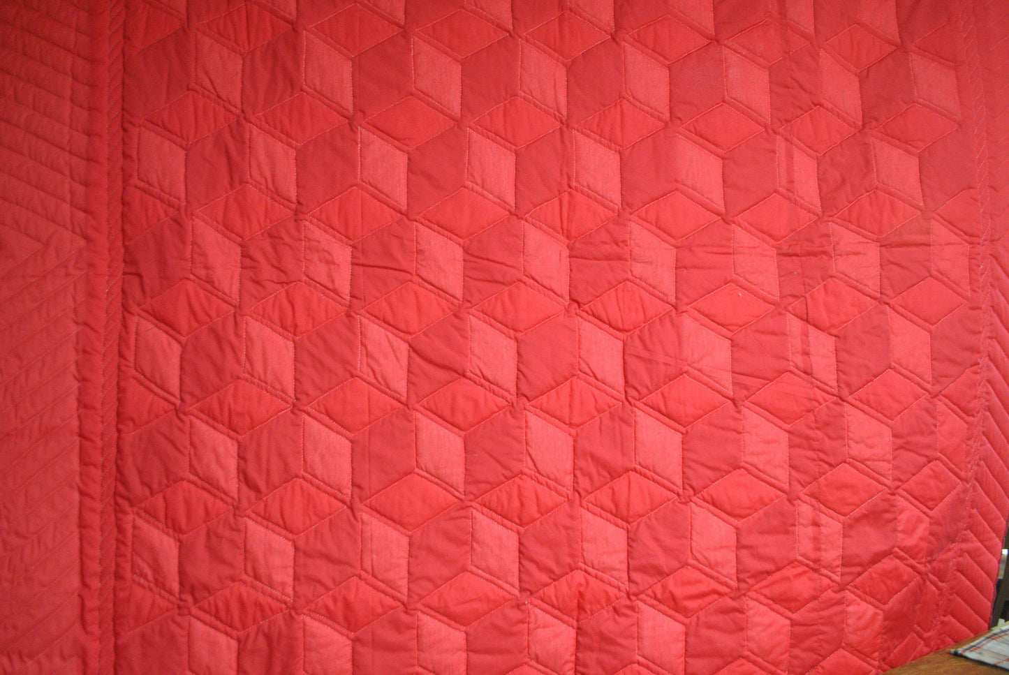 Back of quilt showing tumbling blocks outlined by quilting