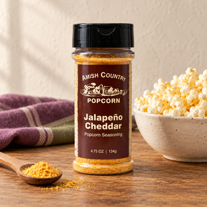 Jalapeño Cheddar Popcorn Seasoning 4.75 oz (134g) beside popcorn on a wooden table