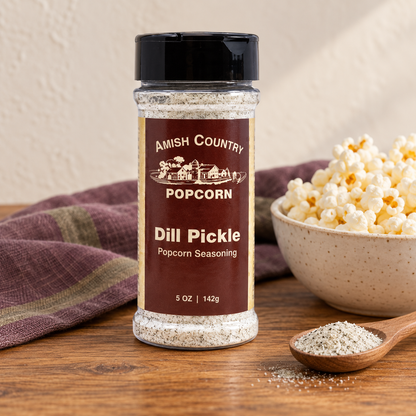 Dill Pickle Popcorn Seasoning 5 oz (142g) beside popcorn on a wooden table