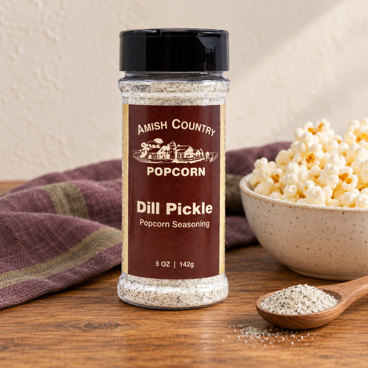 Dill Pickle Popcorn Seasoning 5 oz (142g) beside popcorn on a wooden table