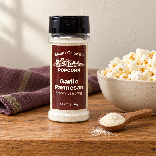 Garlic Parmesan Popcorn Seasoning 5.25 oz (148g) beside popcorn on a wooden table