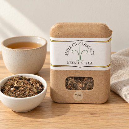 Molly's Farmacy Keen Eye tea, 1/2 oz, beside loose tea and a cup. Styled scene based on the genuine product photo.