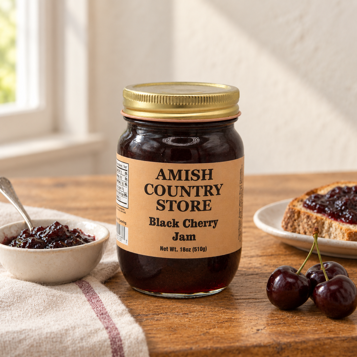 Amish Country Store Black Cherry Jam 18 oz jar beside dark cherry jam, toast and cherries.