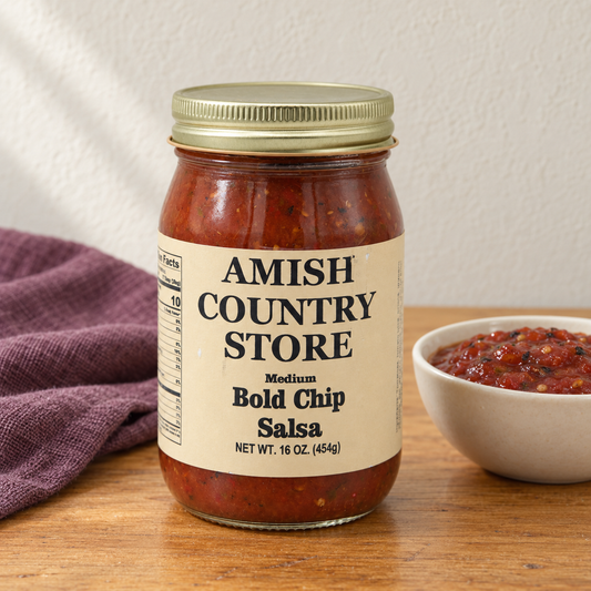 Spicy Roasted Pepper Salsa (Bold Chip) in its original labeled jar with a small serving beside it on a warm wood table.