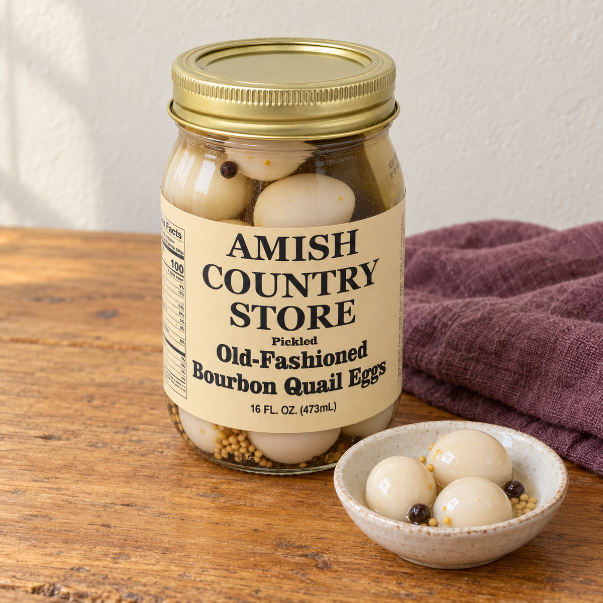 Pickled Old-Fashioned Bourbon Quail Eggs (16 oz) in its original labeled jar with a small serving beside it on a warm wood table.