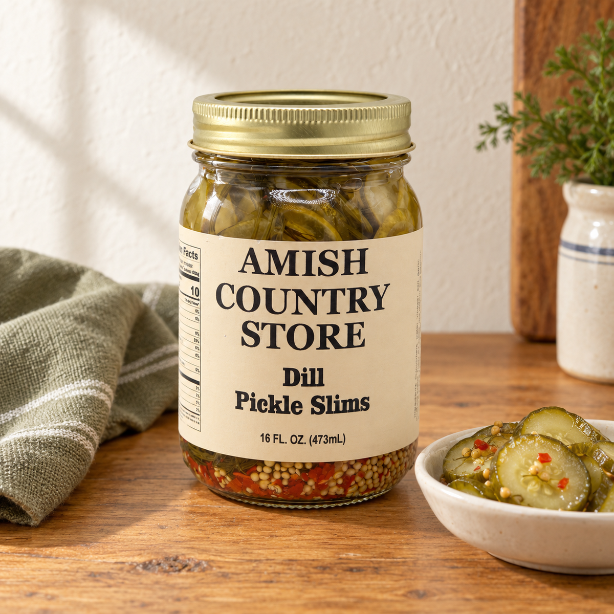 Amish Country Store Dill Pickle Slims 16 fl oz jar with thin dill pickle slices, mustard seeds and pepper flecks.