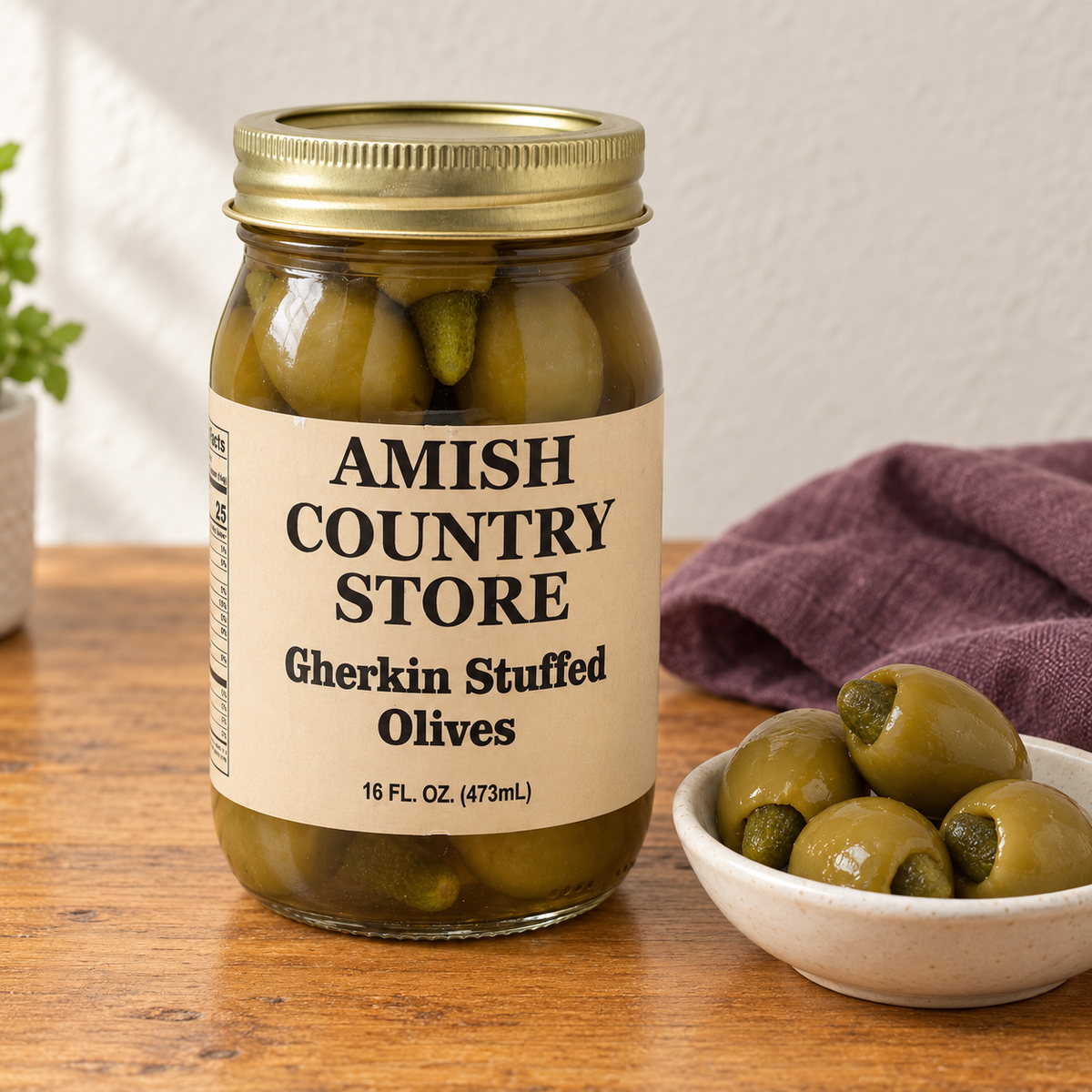 Gherkin Stuffed Olives in its original labeled jar with a small serving beside it on a warm wood table.