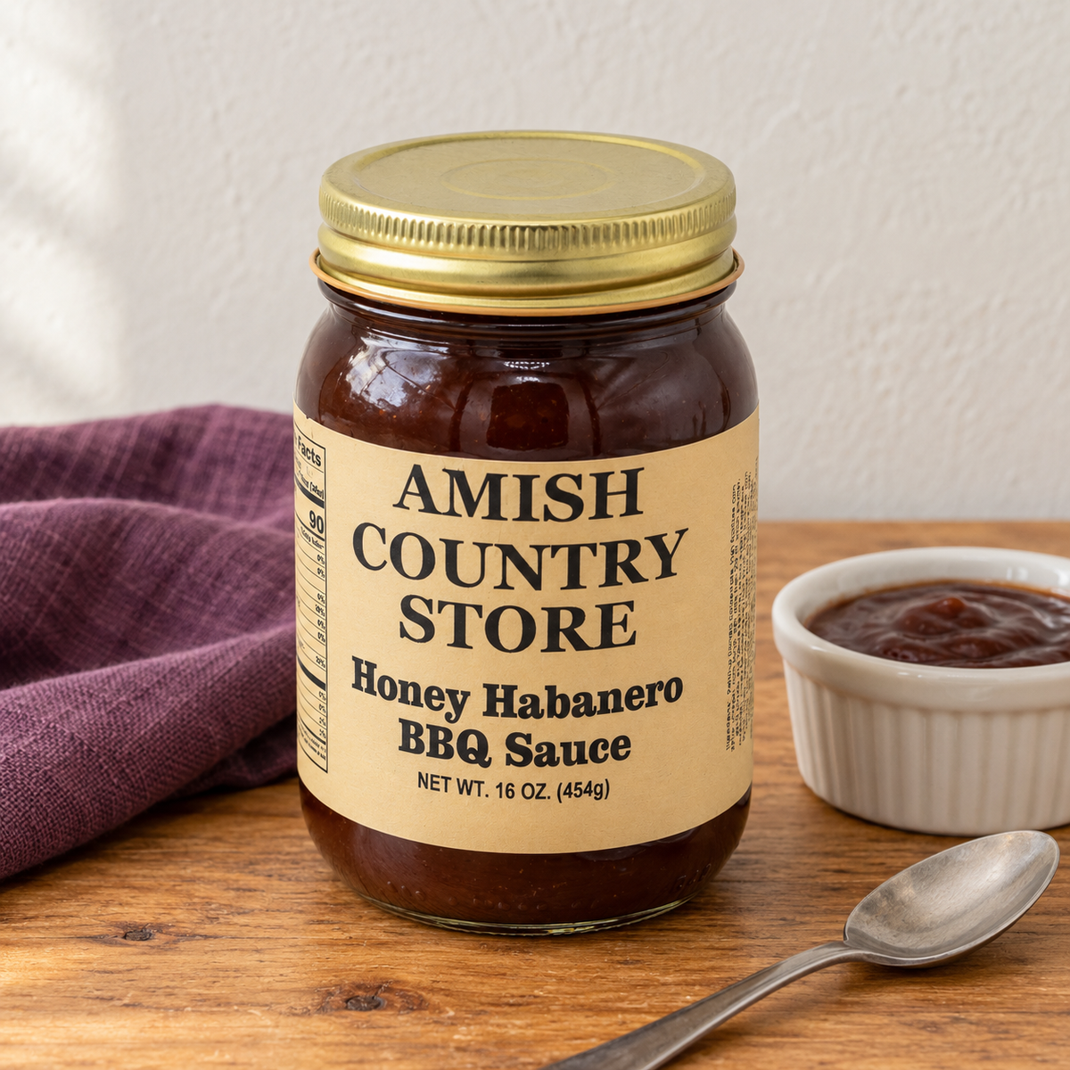 Amish Country Store Honey Habanero BBQ Sauce,16oz jar beside a small dish of dark barbecue sauce.