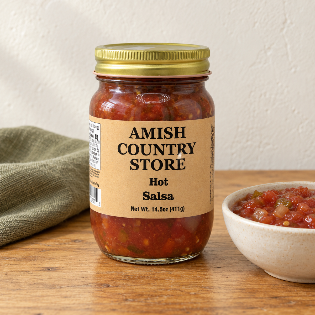 Amish Country Store Hot Salsa,14.5oz jar beside a bowl of chunky tomato salsa.