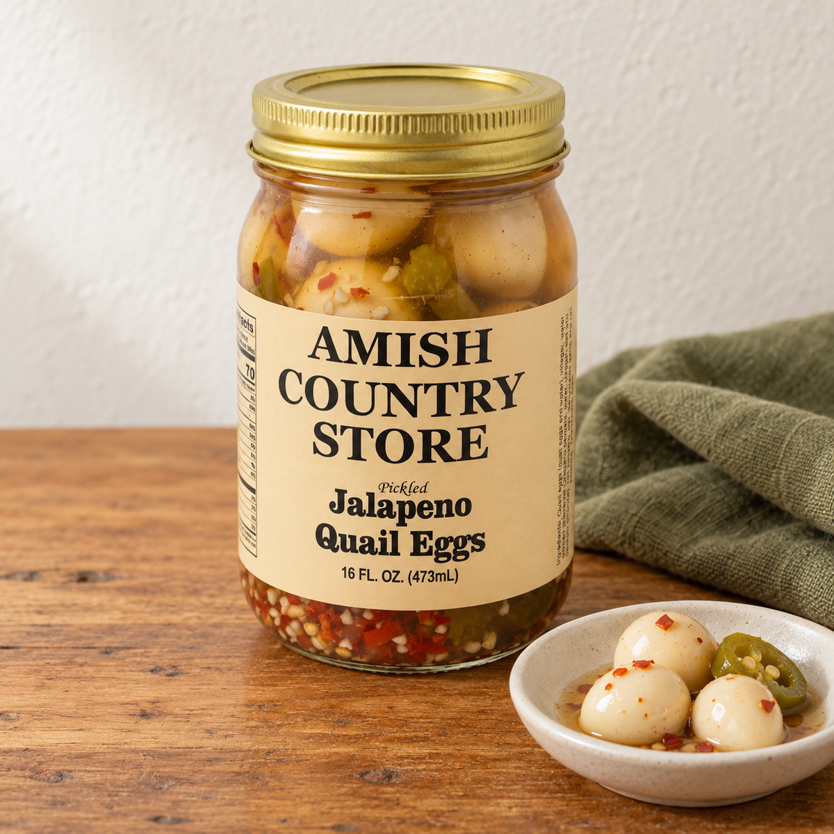 Pickled Jalapeño Quail Eggs (16 oz) in its original labeled jar with a small serving beside it on a warm wood table.