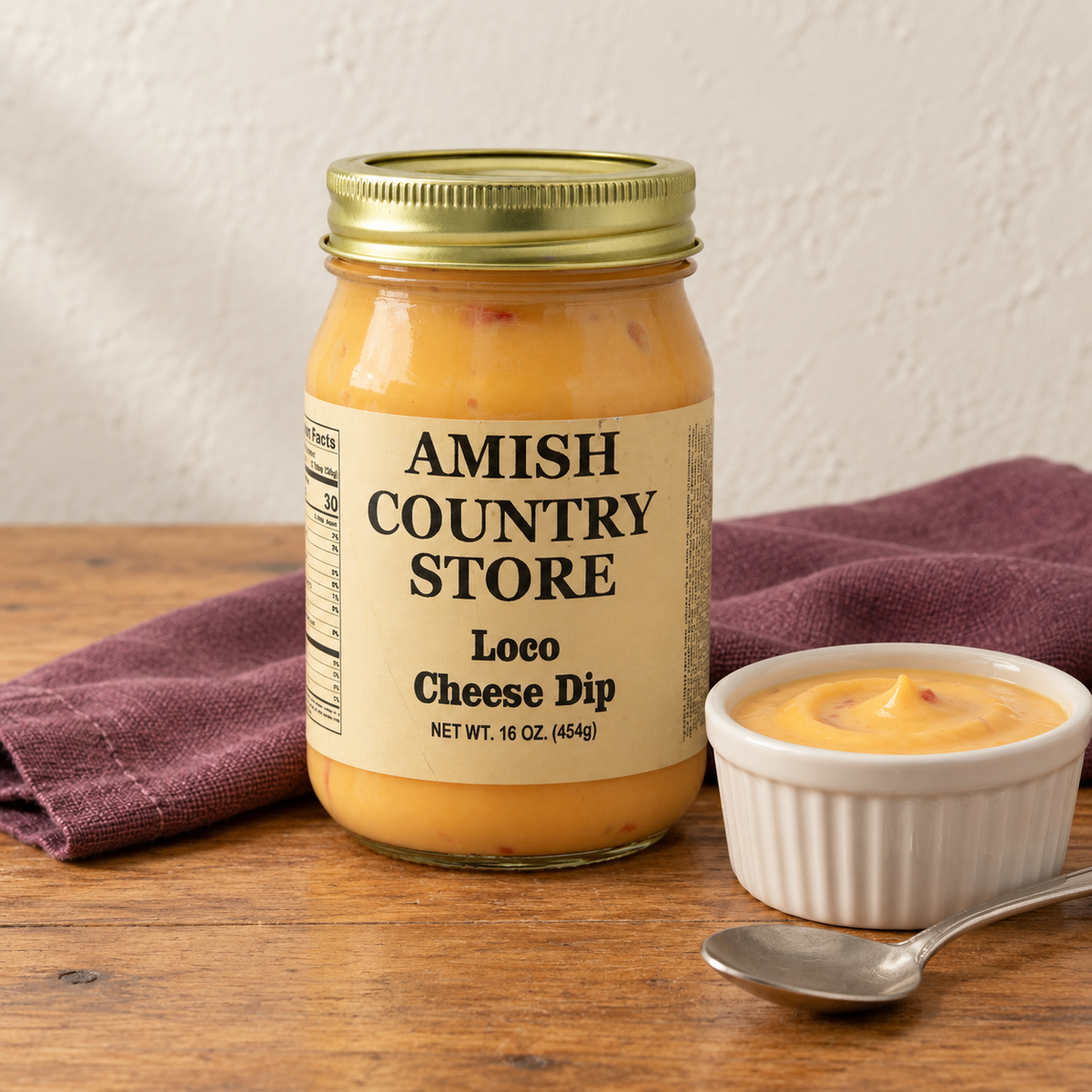 Amish Country Store Loco Cheese Dip,16oz jar beside a small dish of golden cheese dip.