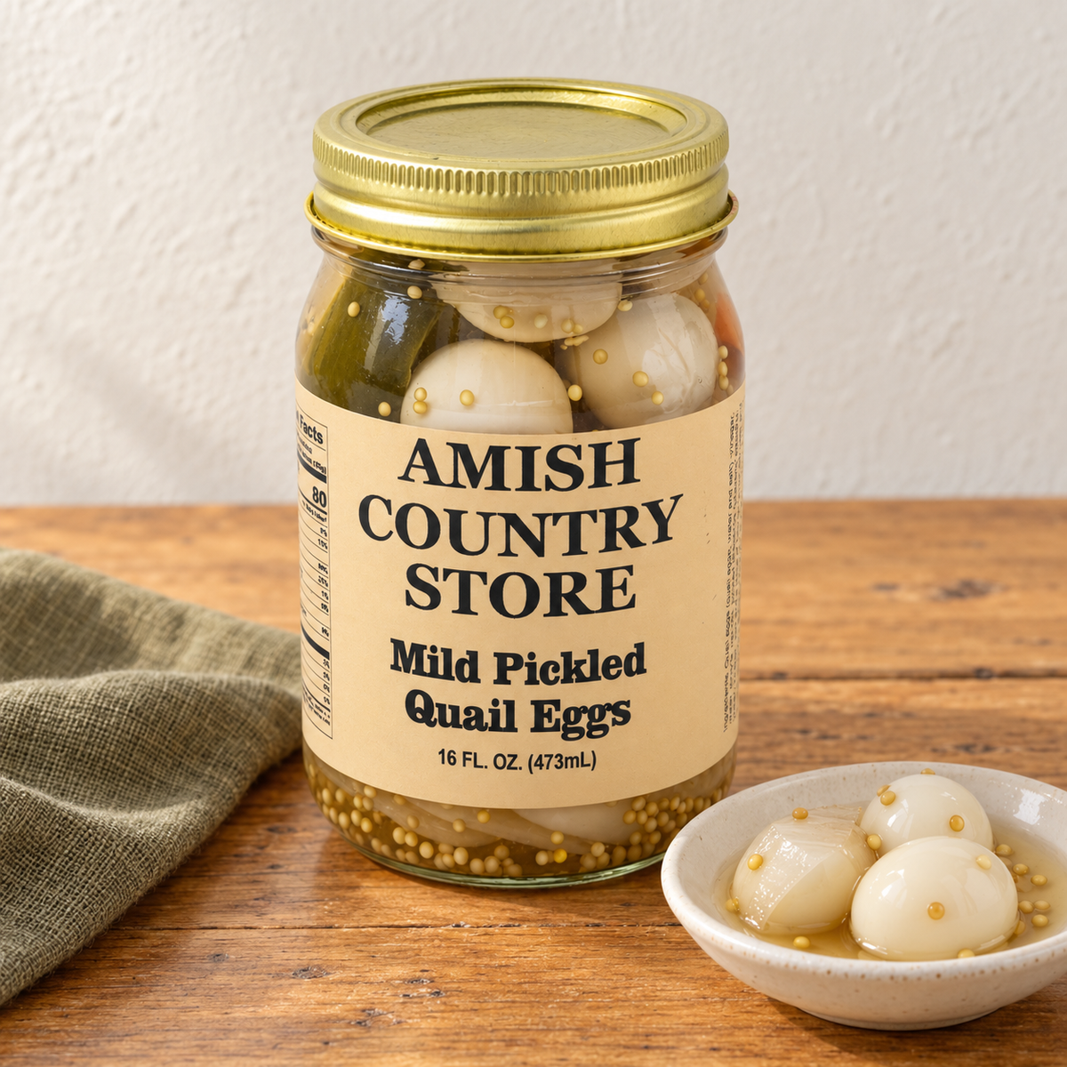 Mild Pickled Quail Eggs (16 oz) in its original labeled jar with a small serving beside it on a warm wood table.