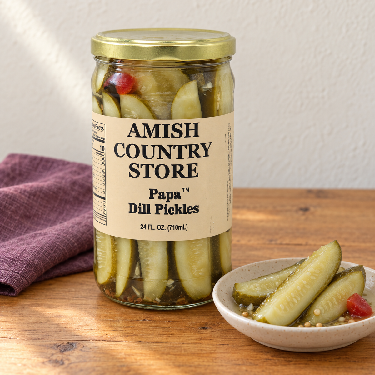 Papa Dill Pickles with Jalapeño in its original labeled jar with a small serving beside it on a warm wood table.