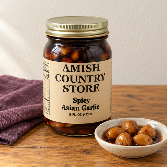 Amish Country Store Spicy Asian Garlic,16fl oz jar beside amber garlic cloves in dark marinade.