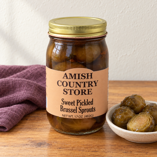 Amish Country Store Sweet Pickled Brussel Sprouts,17oz jar beside a small serving in an ivory dish.