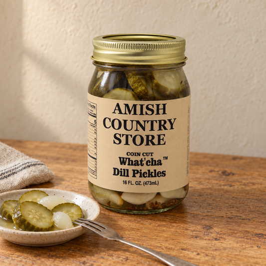 16 fl oz What’cha Dill Pickles jar beside coin-cut dill pickles and pickled onions in a dish.