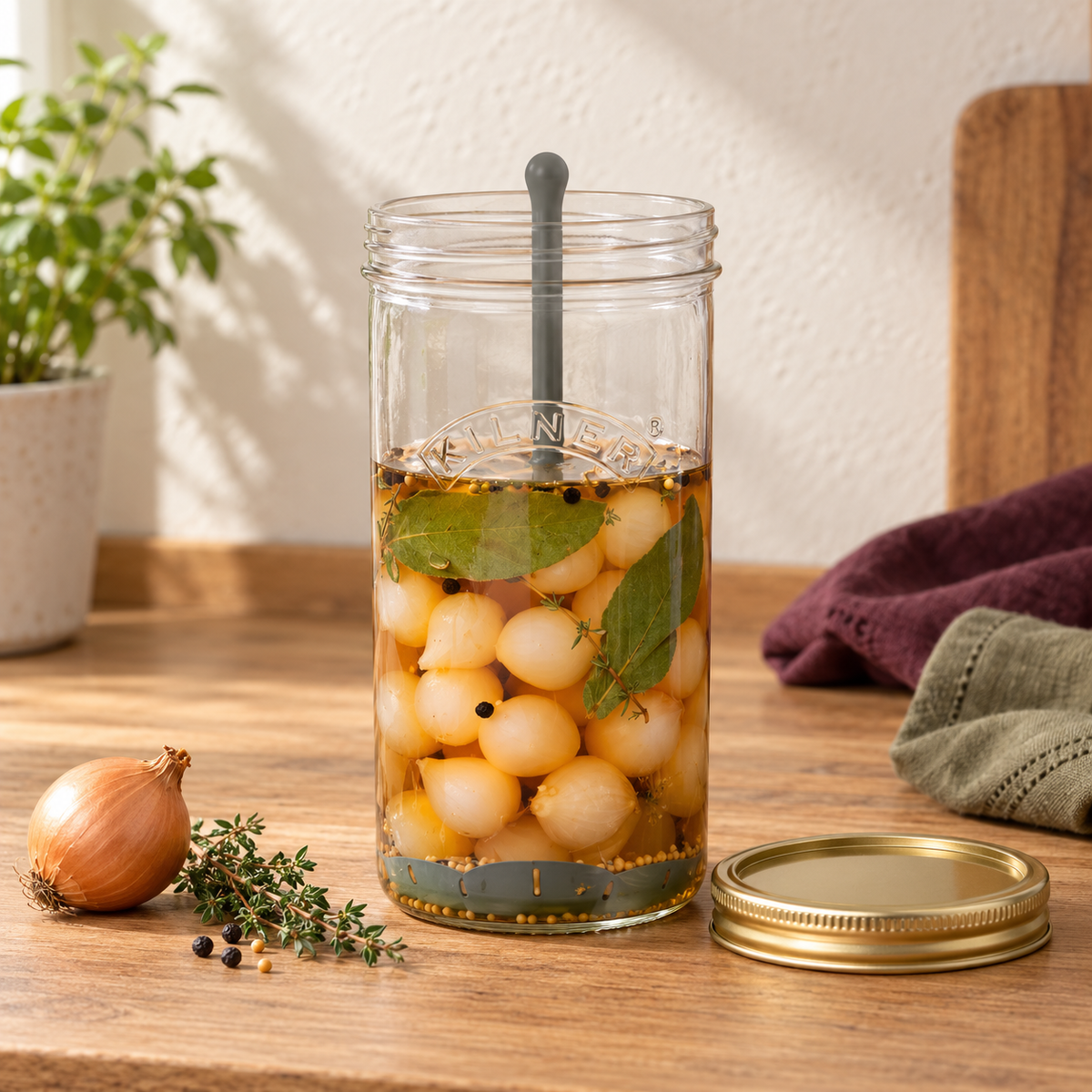 One Kilner 34 US fl oz pickle jar with its grey lifter and gold lid, shown holding pickled onions.