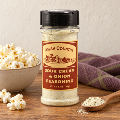 Sour Cream & Onion Popcorn Seasoning 5 oz (142g) beside popcorn on a wooden table