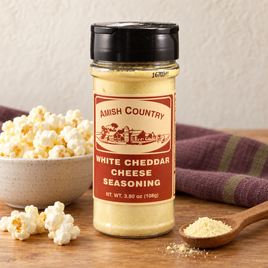 White Cheddar Cheese Popcorn Seasoning 3.80 oz (108g) beside popcorn on a wooden table