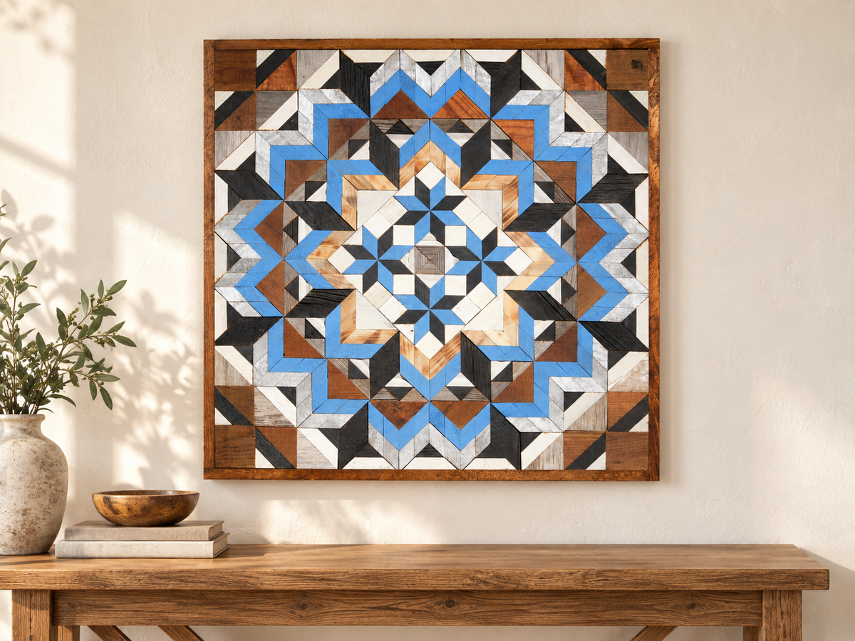 S1183 — 30.5 inch Amish reclaimed wood barn quilt, blue, white, charcoal and natural wood geometric flower with four small blue-and-black stars around the center, displayed on an entryway wall above an oak console