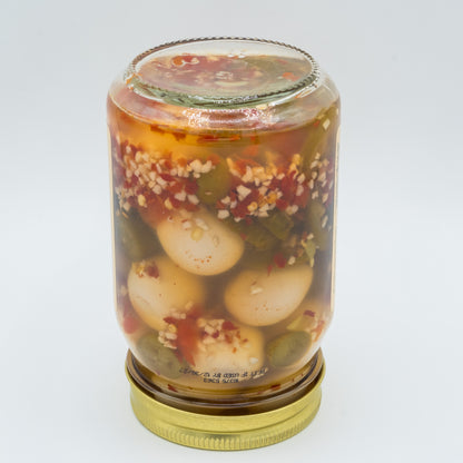 Jar of pickled vegetables with a gold lid on a white background