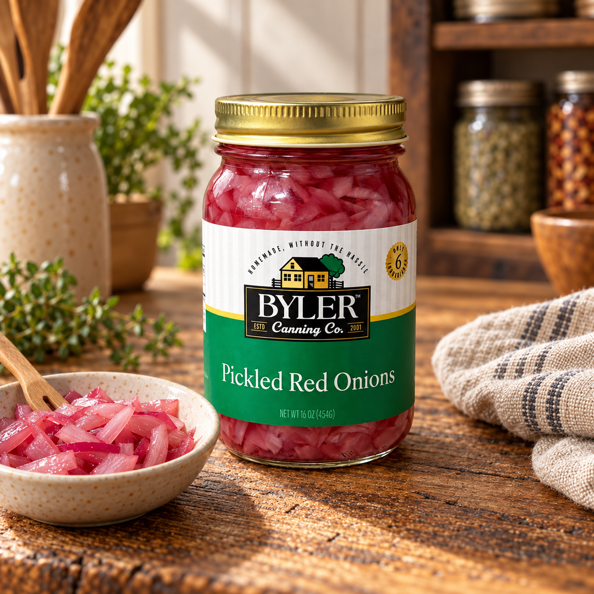 Byler Canning Co. Pickled Red Onions, 16 oz jar, in a warm farmhouse pantry beside a bowl of pickled onions.